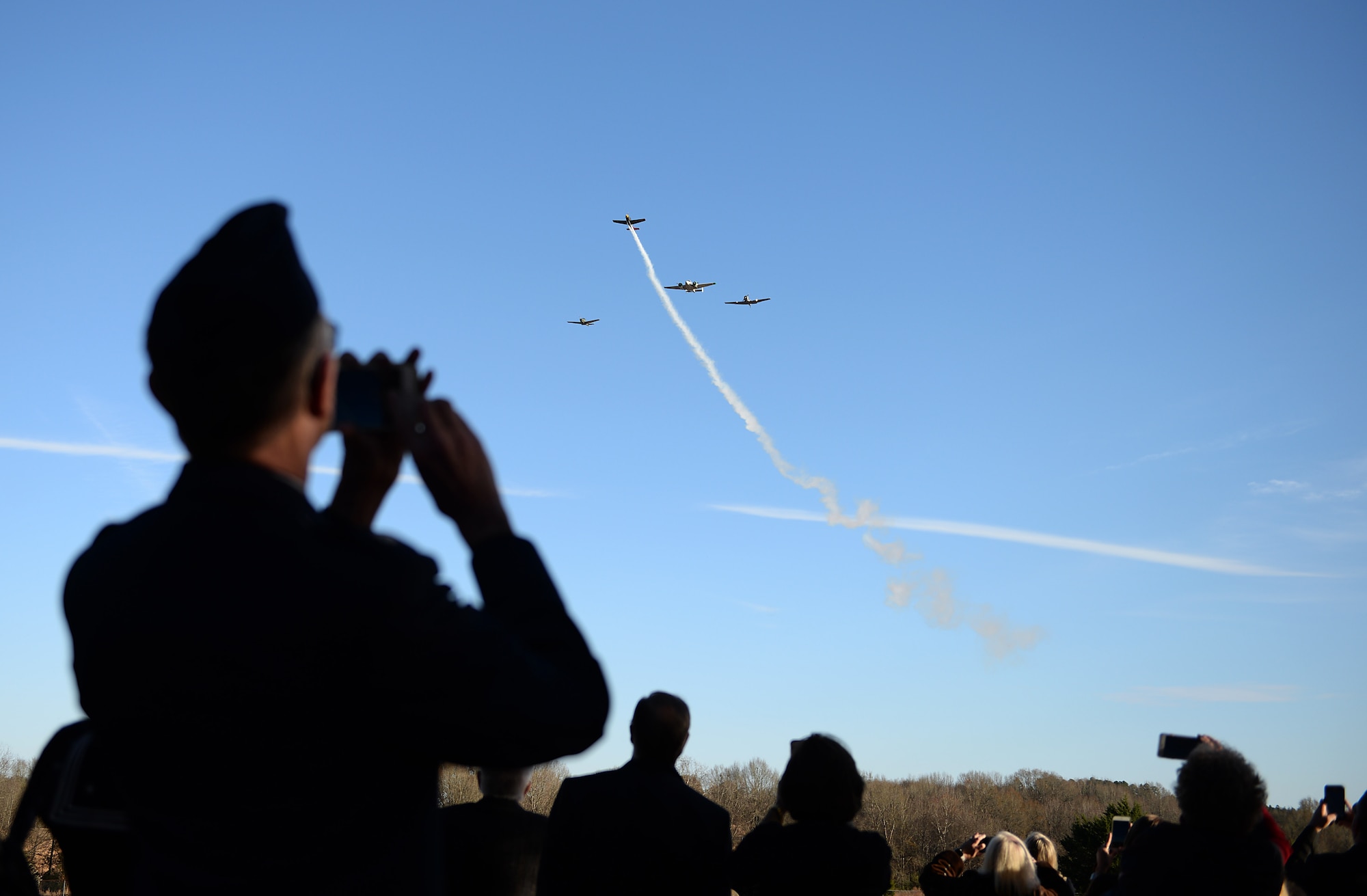 A family member of former Army Air Corps Capt. Charles T. Hull records a four-ship formation during a funeral and burial service with full military honors Dec. 4, 2019, at Duck Hill Cemetery in Winona, Miss. Hull, a decorated World War II bomber pilot who survived 25 missions in the European Theater, continued his love of travel and flying after his military career with his personal aircraft and traveled to all 50 states, 74 countries and even crossing the Arctic Circle four times. (U.S. Air Force photo by Airman Hannah 1st Class Bean)
