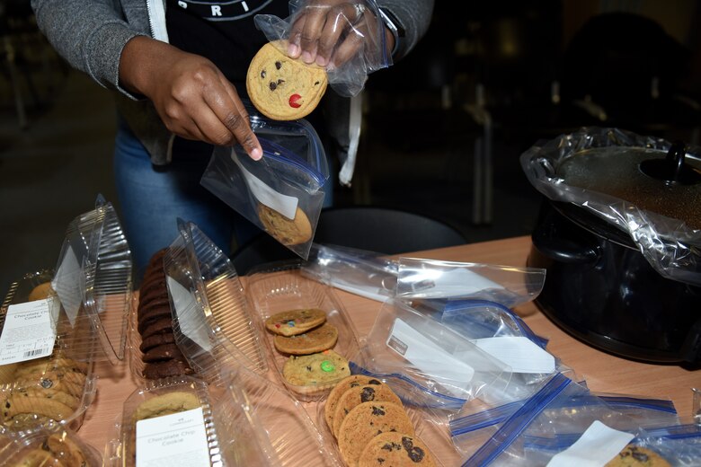 A volunteer sets out desert at the first ever Mid-Shift Chili Fest at Royal Air Force Lakenheath, England, Dec. 5, 2019. The Chili Fest was the first of iteration hosted by the RAF Lakenheath Community Action Team and consisted of a variety of chili, cookies, apple cider, an array of games, and merchandise from different organizations. (U.S. Air Force photo by Airman 1st Class Rhonda Smith)