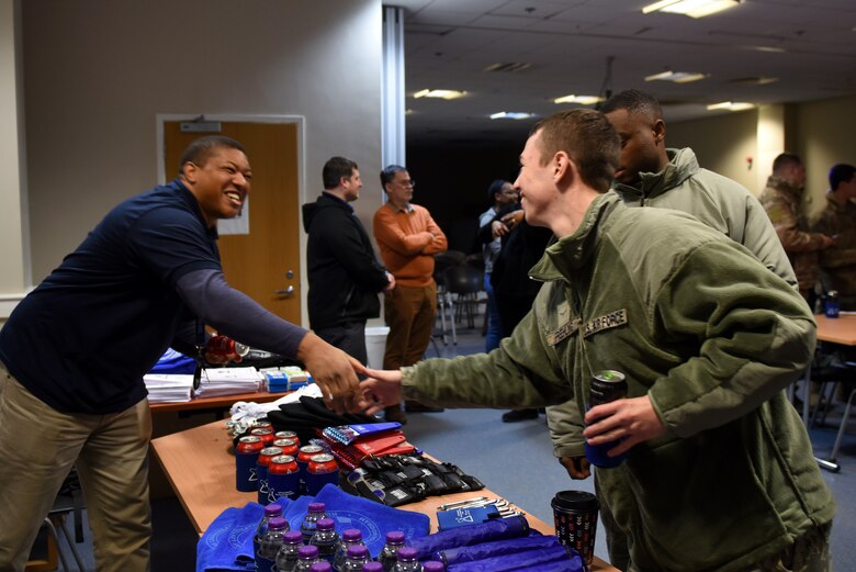 A volunteer greets Liberty Wing Airmen at the first ever Mid-Shift Chili Fest event at Royal Air Force Lakenheath, England, Dec. 5, 2019. The event consisted of a variety of chili, cookies, apple cider, an array of games, and merchandise from different helping agencies from across the Liberty Wing. (U.S. Air Force photo by Airman 1st Class Rhonda Smith)