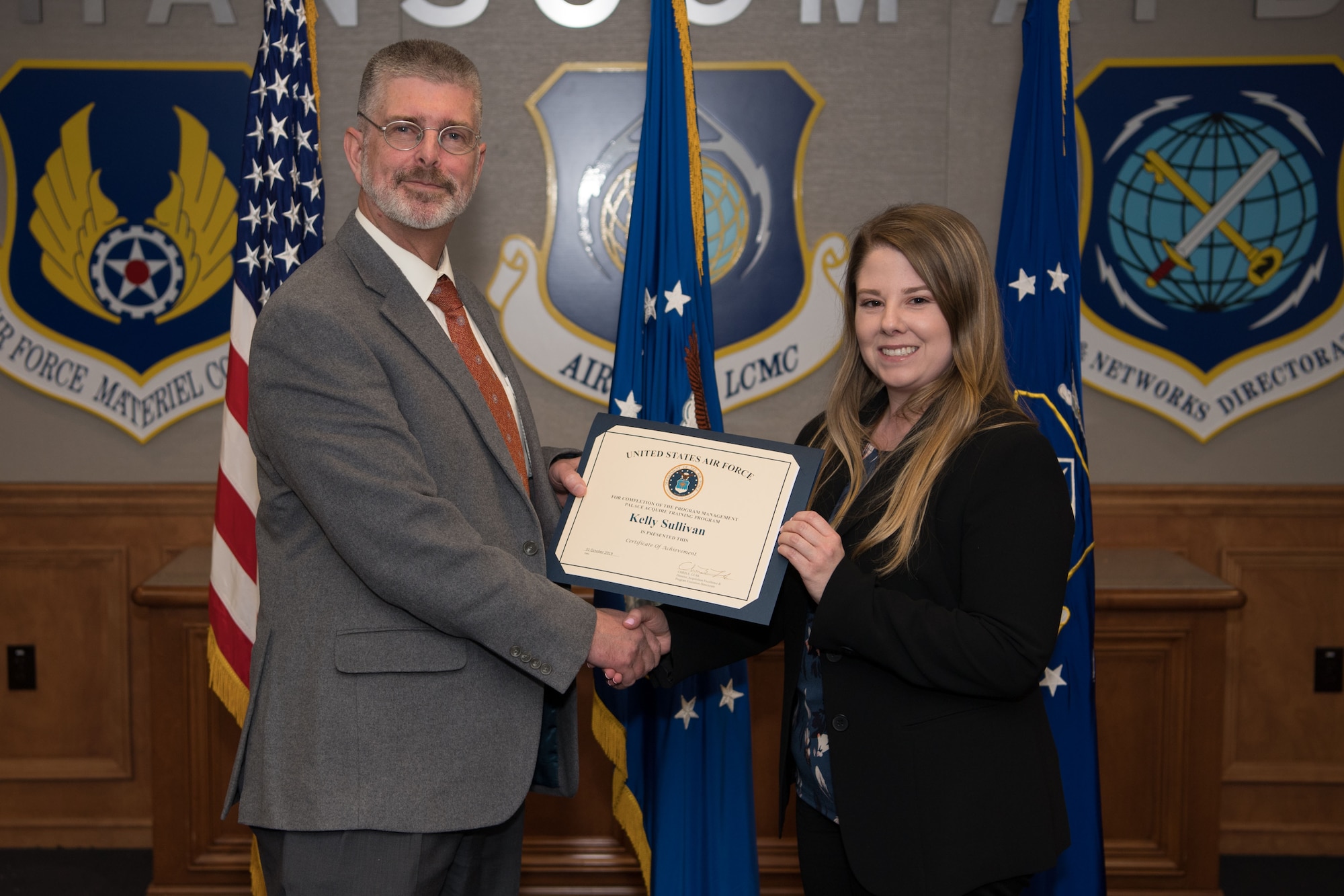 Kelly Sullivan, a PALACE Acquire graduate and program manager for the Digital Directorate, receives a certificate from Scott Owens, deputy director of Command, Control, Communications, Intelligence and Networks, during a graduation ceremony for program management trainees at Hanscom Air Force Base, Mass., Dec. 5.