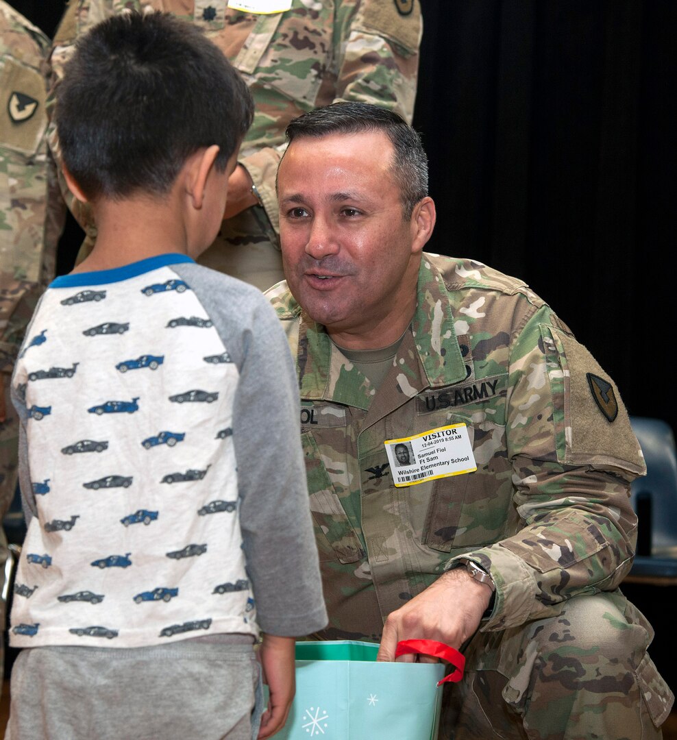Col. Samuel E. Fiol, 502nd Force Support Group commander, presents a gift bag to a student at Wilshire Elementary School in San Antonio Dec. 4 as part of the Adopt a School program. The school is a Title I Campus with 88 percent of students identified as economically disadvantaged.