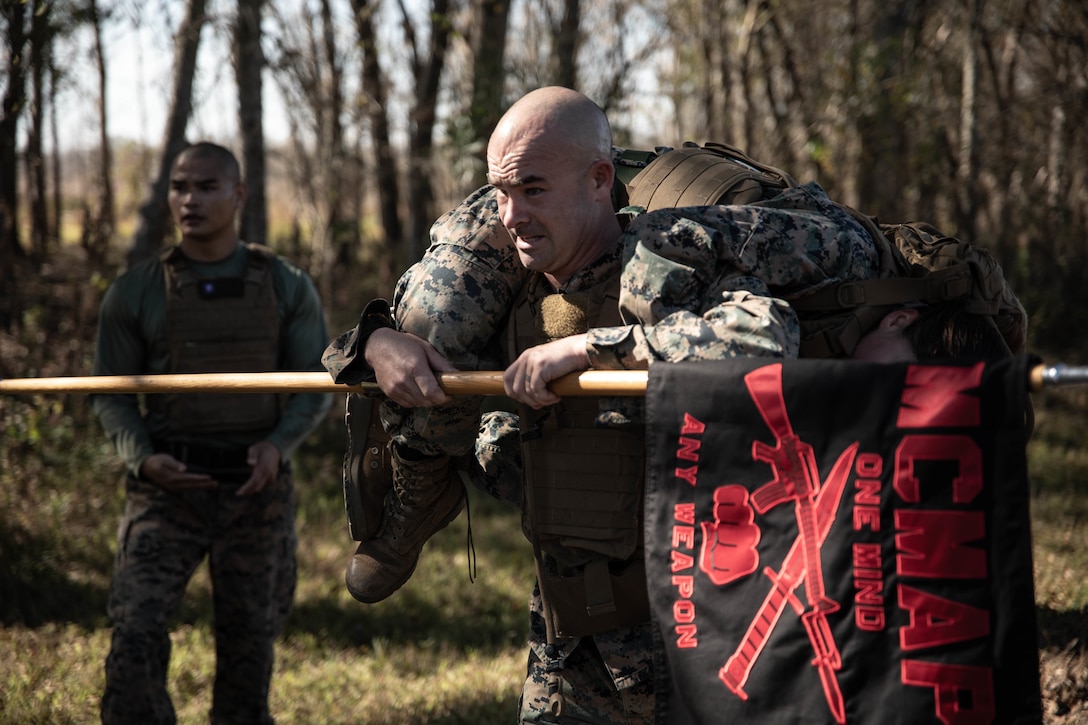 Staff Sgt. Matthew Driggers, fleet readiness center senior enlisted advisor with Marine Light Attack Helicopter Squadron 773, Marine Aircraft Group 49, fireman-carries Sgt. Lynarae Pena, a tactical switching operator with Reserve Base Support, Marine Forces Reserve, to the next objective during the Martial Arts Instructor Course 1-20 aboard Naval Air Station Joint Reserve Base New Orleans, on Dec. 4, 2019. The course consists of both physical and mental challenges to mold Martial Arts Instructors. (U.S. Marine Corps photo by Pfc. Colby Bundy)