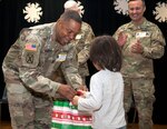 Sgt. Maj. Danang McKay, 502nd Force Support Group command sergeant major, gives a personalized gift bag to a student at Wilshire Elementary School in San Antonio Dec. 4 as part of the Adopt a School program. To help ensure the students at the school are warm during the winter months, 502nd FSG volunteers collected coats, socks, and toys to give needy children as part of the program.