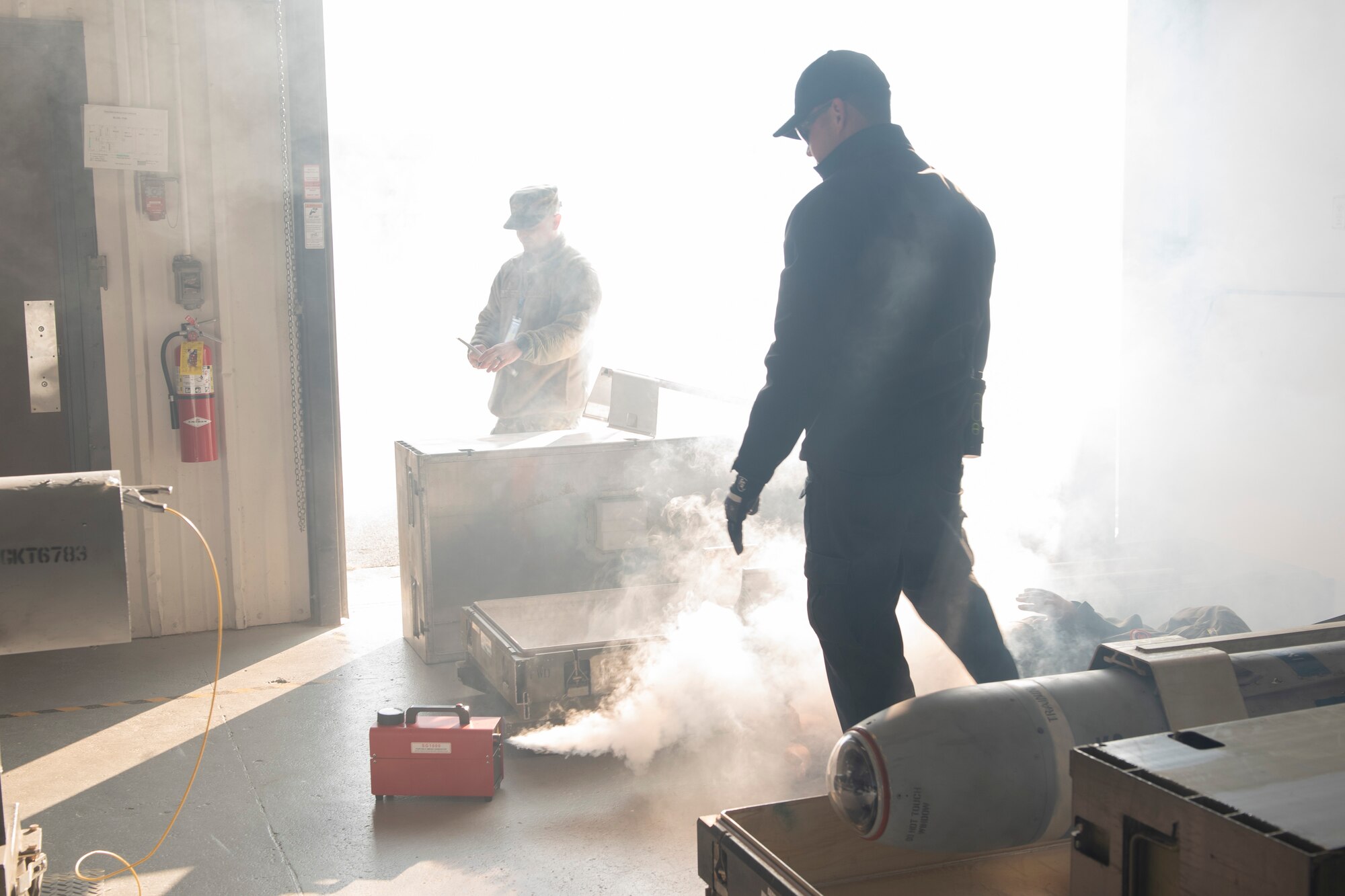A photo of a fire inspector setting up a smoke machine for an evacuation drill.