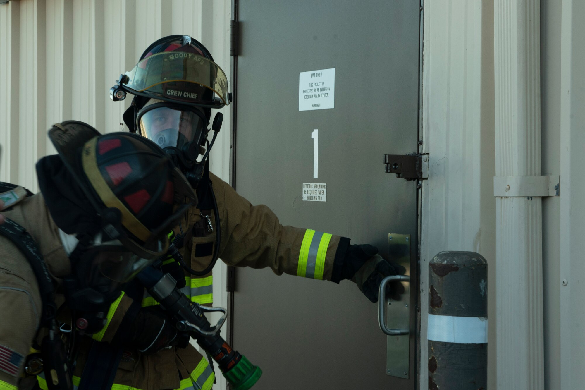 A photo of an Airman checking a door handle for heat during an evacuation drill.