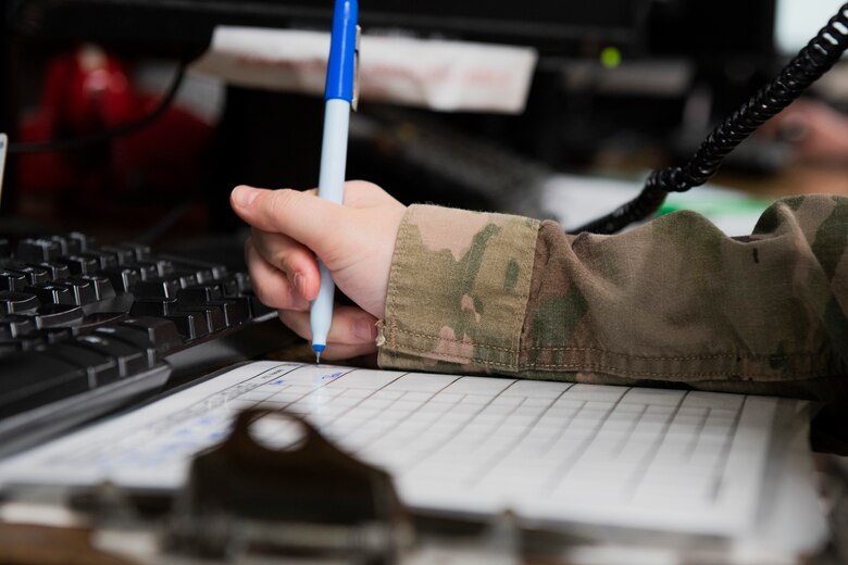 A photo of an Airman writing down flight routes