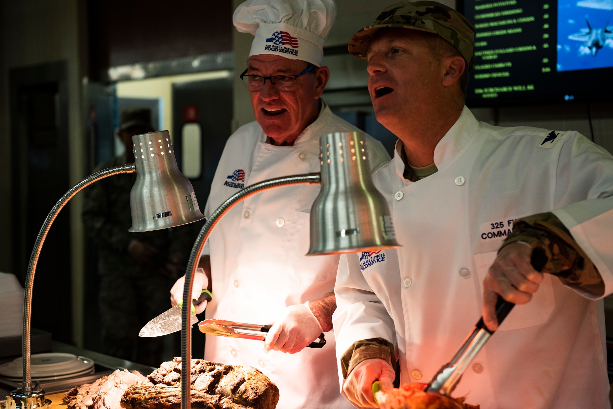 Florida Congressman Neal Dunn, left, and U.S. Air Force Col. Brian Laidlaw, 325th Fighter Wing Commander, right, serve different varieties of meat at the 325th Force Support Squadron holiday meal at Tyndall Air Force Base, Florida, Nov. 28, 2019. Meal attendees were served by commanders, chiefs, first sergeants, and special guests of the 325th Fighter Wing, to honor the service and sacrifice of military members past and present. (U.S. Air Force photo by Staff Sgt. Magen M. Reeves)