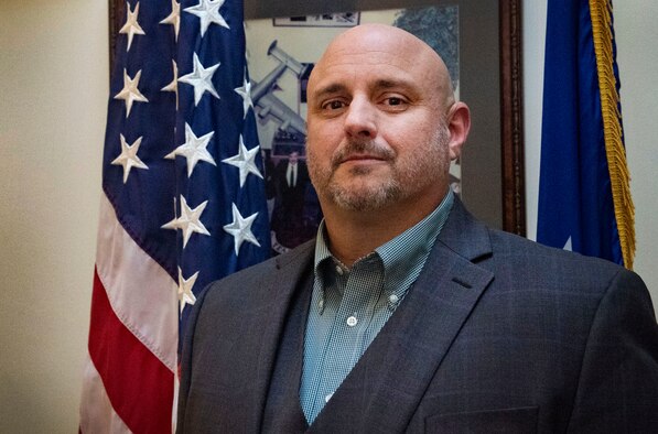 Rob Schenk, 66th Logistics Readiness Squadron and installation deployment officer, poses for a photo outside his office in the Brown Building on Hanscom Air Force Base, Dec. 4. As the IDO, Schenk is responsible for the rotation of deplopying service members and civilians throughout the New England and parts of New York. (U.S. Air Force photo by Lauren Russell)