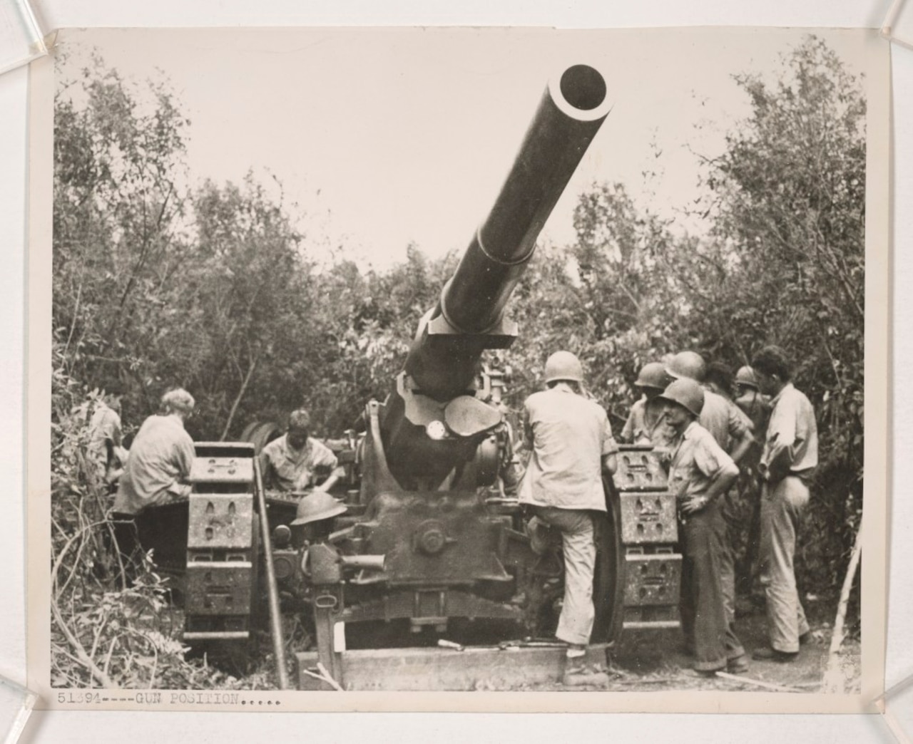 A handful of Marines work on a massive 155 mm gun surrounded by jungle