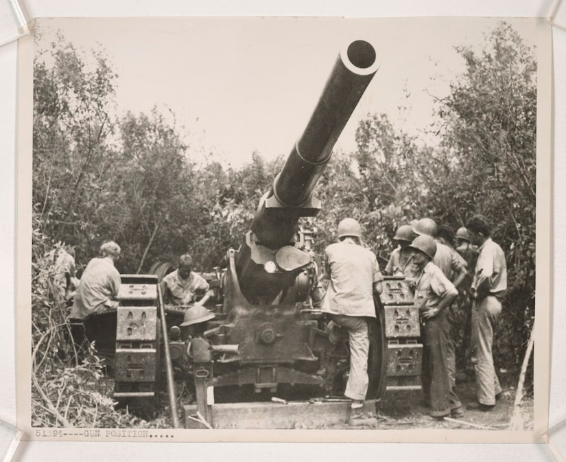 A handful of Marines work on a massive 155 mm gun surrounded by jungle