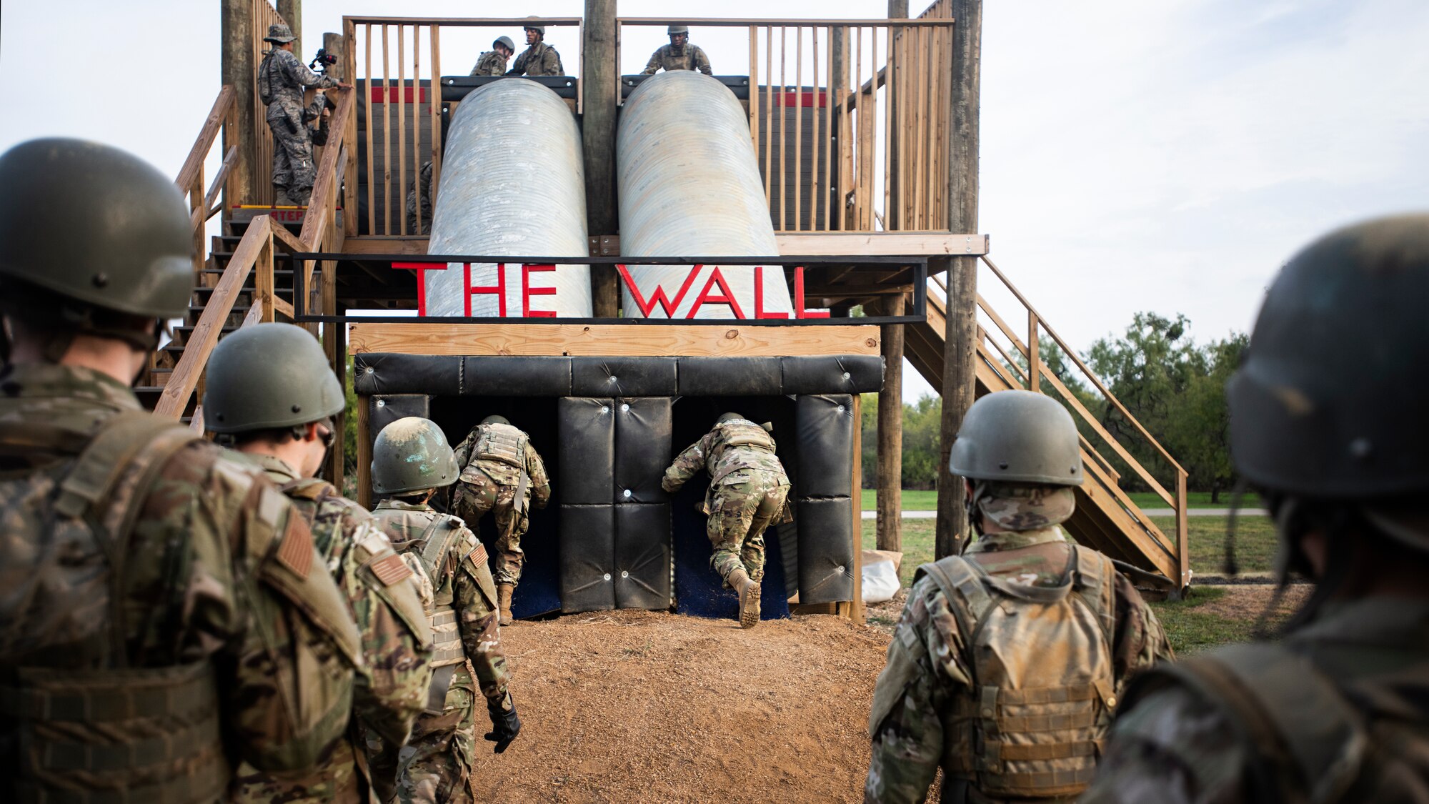 Basic military trainees begin an obstacle known as “The Wall”