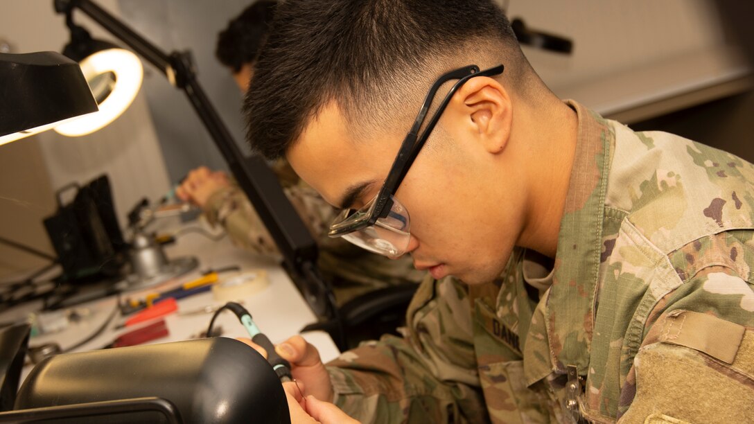 An Army student at the Defense Information School solders electronic equipment in one of the school's classrooms.