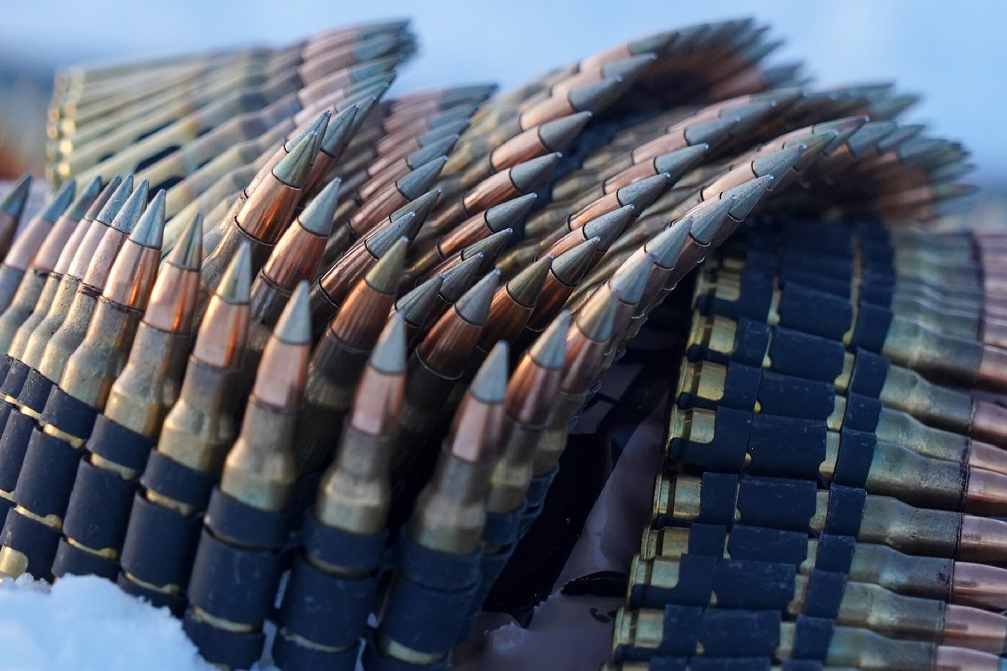 Linked belts of 7.62mm ammunition lays coiled on the ground as paratroopers assigned to the 2nd Battalion, 377th Parachute Field Artillery Regiment, 4th Infantry Brigade Combat Team (Airborne), 25th Infantry Division, U.S. Army Alaska, use M240B, and M2 machine guns while conducting live-fire qualification at Grezelka range, on Joint Base Elmendorf-Richardson, Alaska, Dec. 5, 2019. The Soldiers practiced identifying, and engaging targets at varying distances to solidify their proficiency with the weapons in sub-arctic conditions.