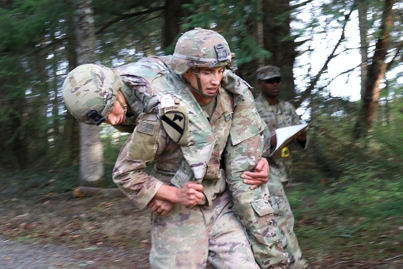 A soldier carries another soldier on his back.