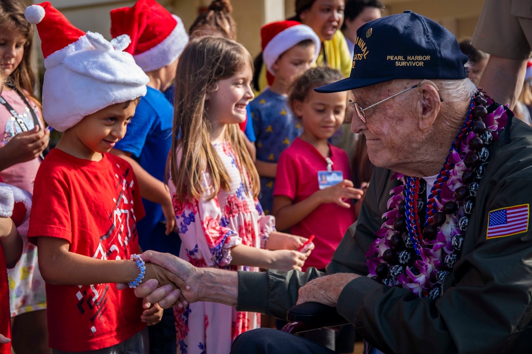 A man in a wheelchair shakes hands with a child.