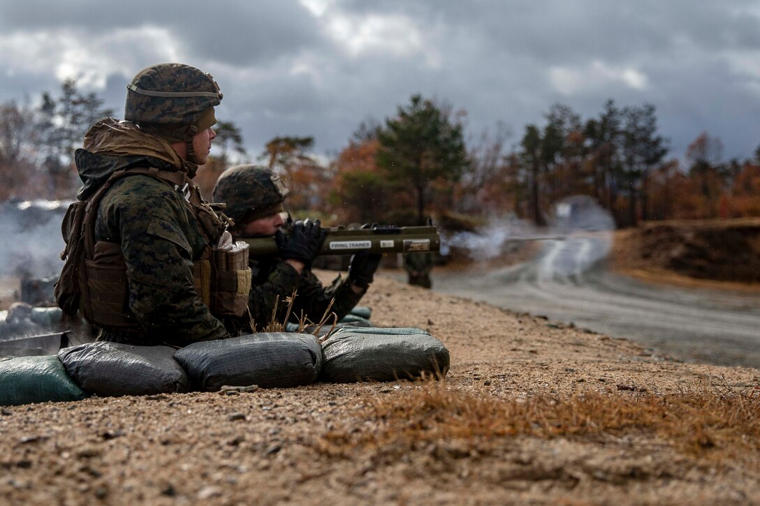 Two Marines fire a weapon.