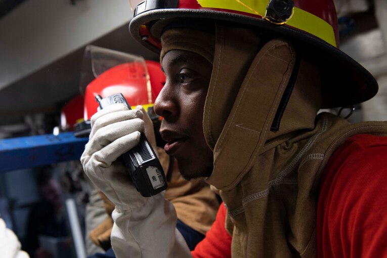 A sailor talks into a radio.