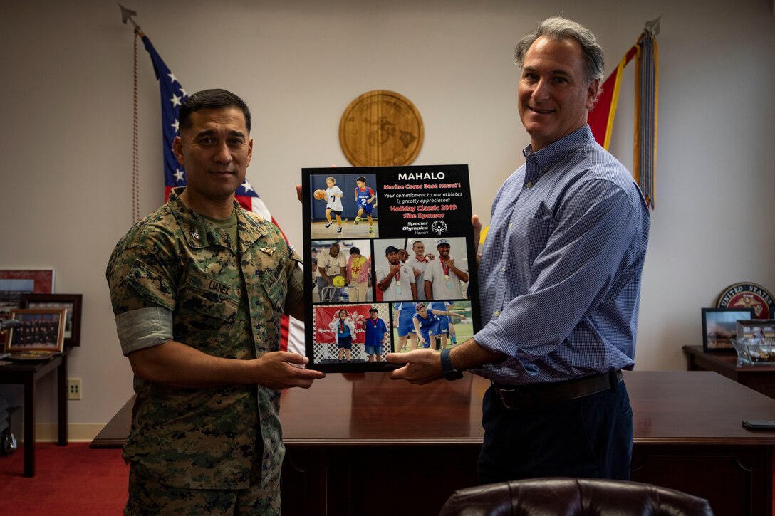 U.S. Marine Corps Col. Raul Lianez, left, commanding officer, Marine Corps Base Hawaii (MCBH), accepts a token of appreciation from Dan Epstein, Chief Operating Officer, Special Olympics Hawaii (SOHI), MCBH, Dec. 4, 2019.  SOHI provides sports training throughout the year and athletic competition in a variety of Olympic sports for persons with intellectual or development disabilities. MCBH began supporting the SOHI event in 1997. (U.S. Marine Corps photo by Lance Cpl. Samantha Sanchez)