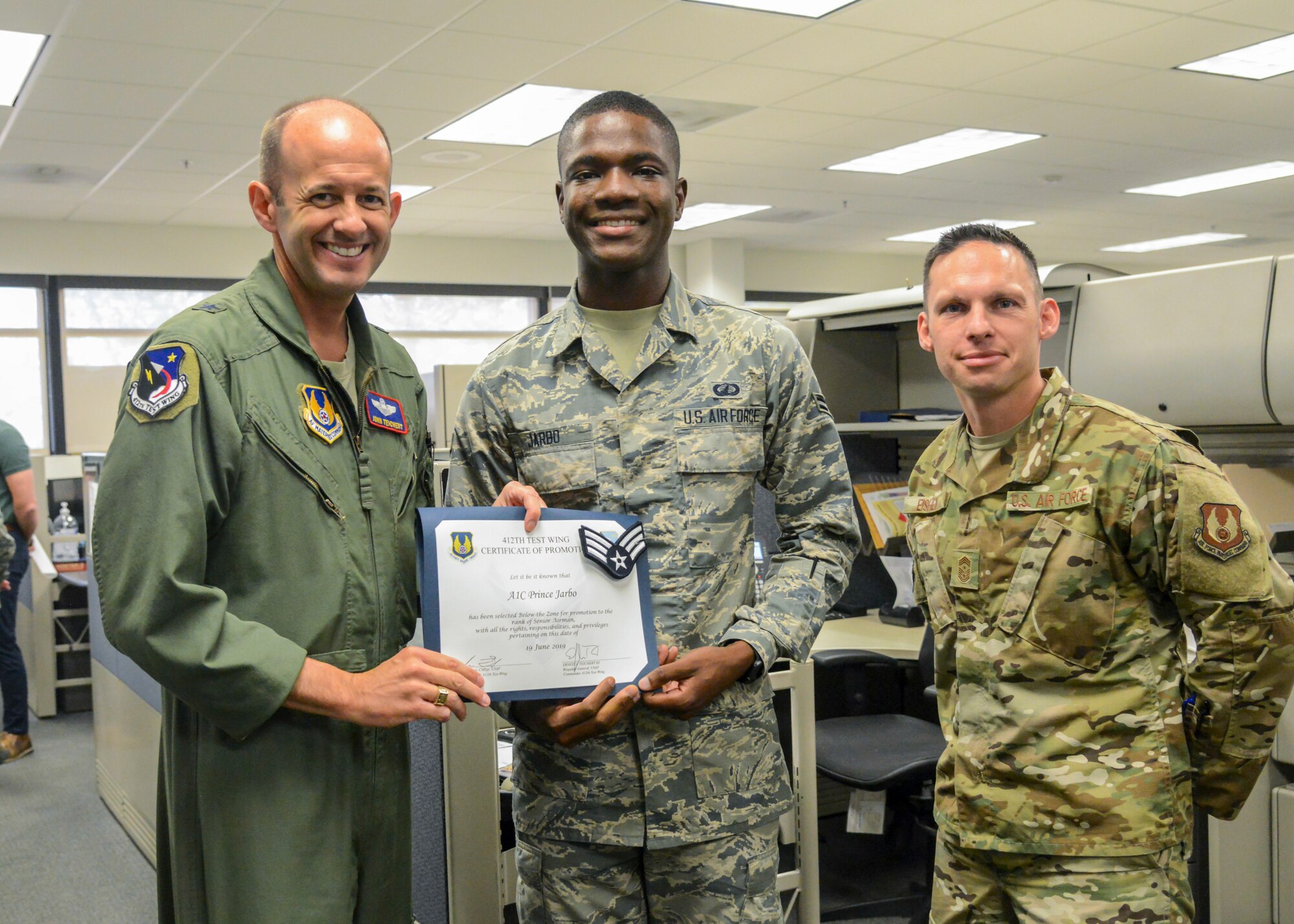 Senior Airman Prince Jarbo, 412th Comptroller Squadron, poses for a photo with Brig. E. John Teichert, 412th Test Wing Commander, and Command Chief Master Sgt. Ian Eishen, 412th Test Wing Command Chief, during his promotion ceremony at Edwards Air Force Base, California, June 19. (Air Force photo by Giancarlo Casem)