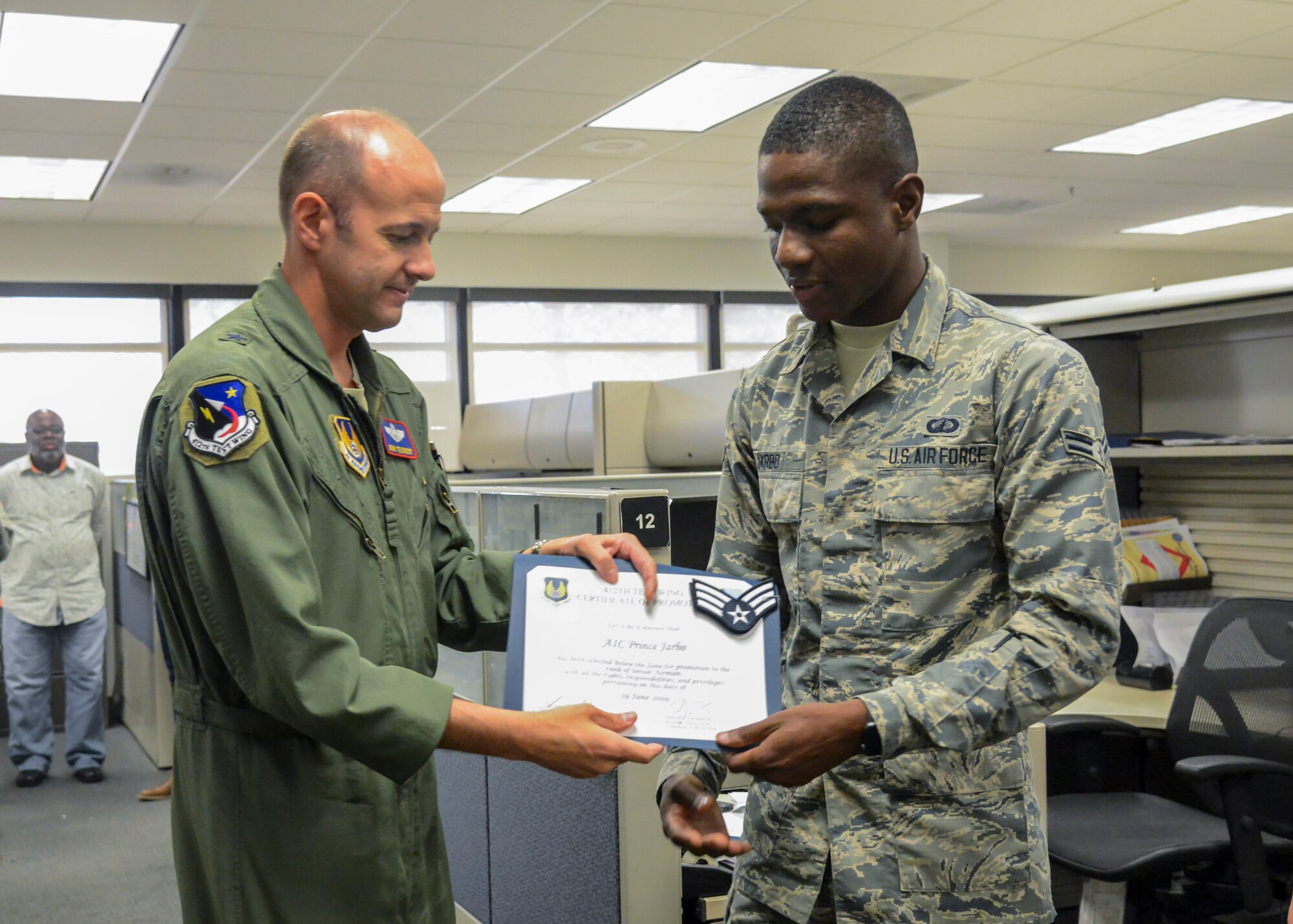 412th Test Wing Commander, Brig. Gen. E. John Teichert, presents a certification of promotion to Senior Airman Prince Jarbo, 412th Comptroller Squadron, June 19. (Air Force photo by Giancarlo Casem)