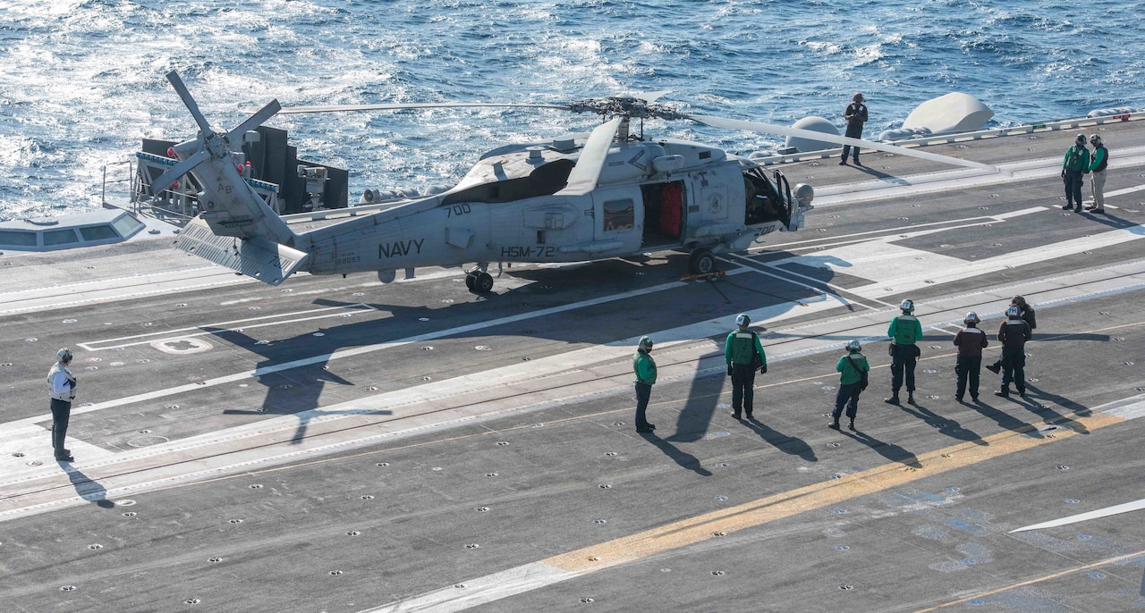 Sailors mill around deck of carrier.