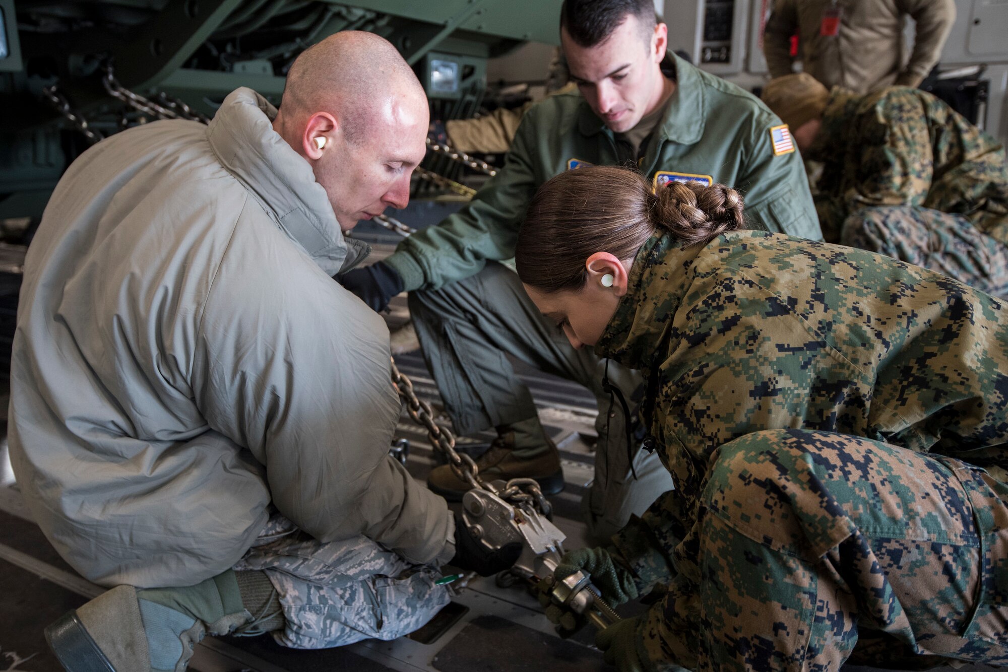 U.S. Reserve Citizen Airmen Staff Sgt. Ilya Zotav, an aerial transportation specialist with the 35th Aerial Port Squadron, and Senior Airman Jake A. Schneider, a C-17 Globemaster III loadmaster with the 732nd Airlift Squadron, both with the 514th Air Mobility Wing, show Marine Corps Lance Cpl. Morgan Malin, an embarkation specialist with Marine Aircraft Group 49, how to secure an ARFF Firetruck P-19R with MAG-49 onto a C-17 with the 732nd AS during a joint training exercise on Joint Base McGuire-Dix-Lakehurst, N.J., on Dec. 8, 2019.