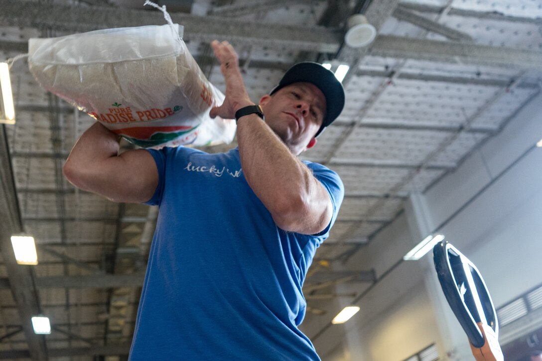 A volunteer lifts a bag of rice