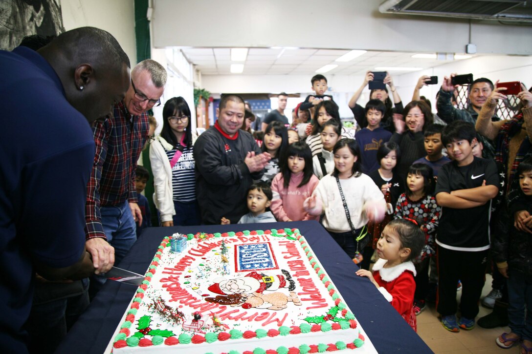 基地司令官らが大きなクリスマスケーキに入刀。米海兵隊基地キャンプ・シュワブで１２月７日、第3８回子どものクリスマスがＵＳＯ（米国慰問団）で開催され、３０人以上のボランティアの隊員や辺野古区住民を中心に、北は国頭村、南は宜野湾市からの家族を含む総勢３００人以上が参加したビッグイベントになりました。