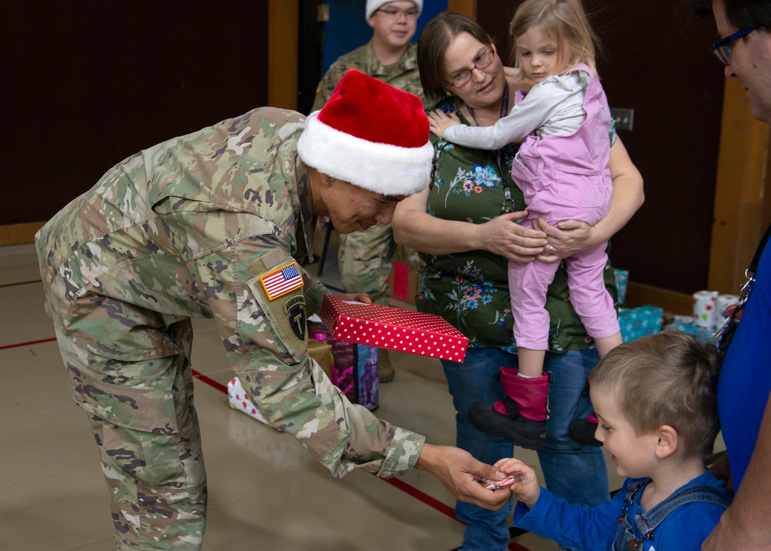 Alaska Army National Guard Sgt. Randall Andrew, an infantryman assigned to the National Guard Readiness Center in Bethel, Alaska, gives a child a gift during Operation Santa Claus in Napakiak, Alaska, Dec. 3, 2019