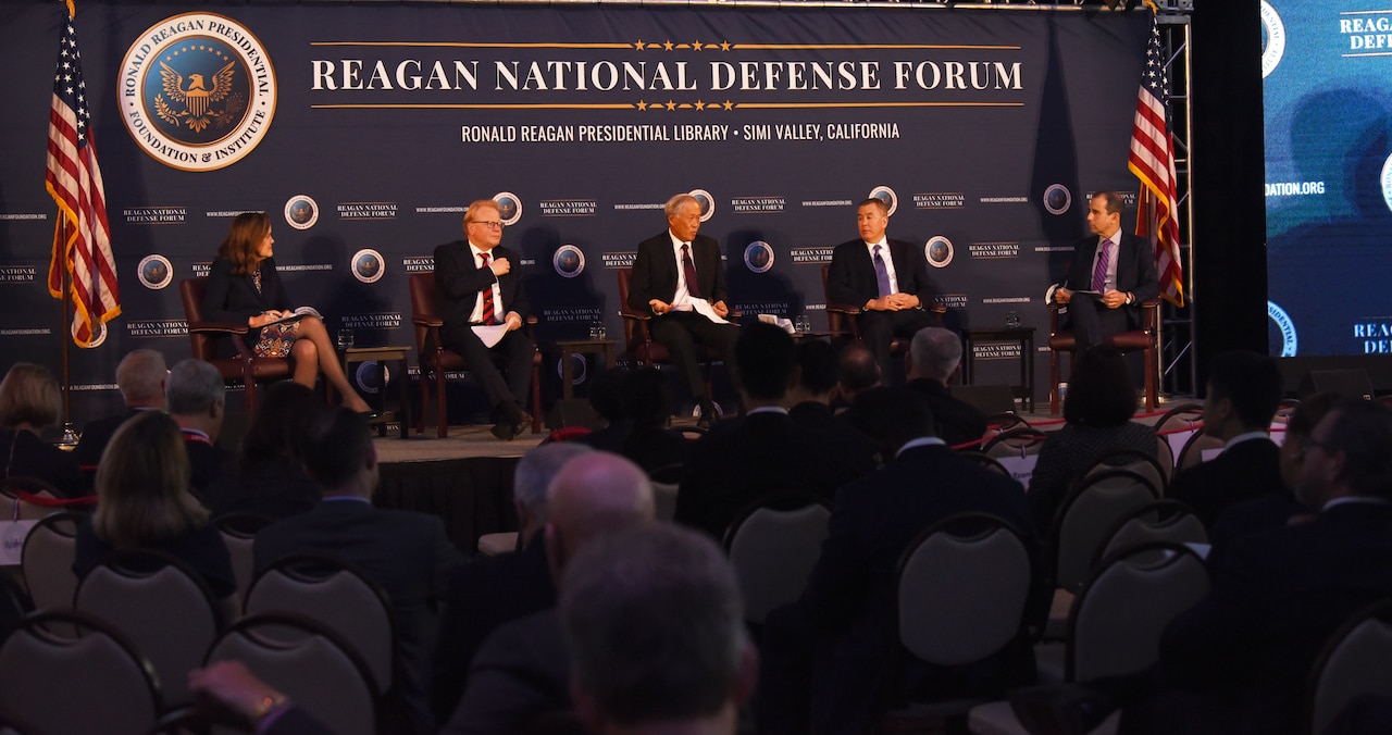 Five-member panel is seated on a stage.
