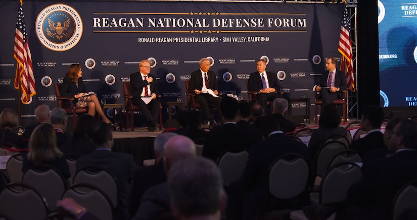Five-member panel is seated on a stage.