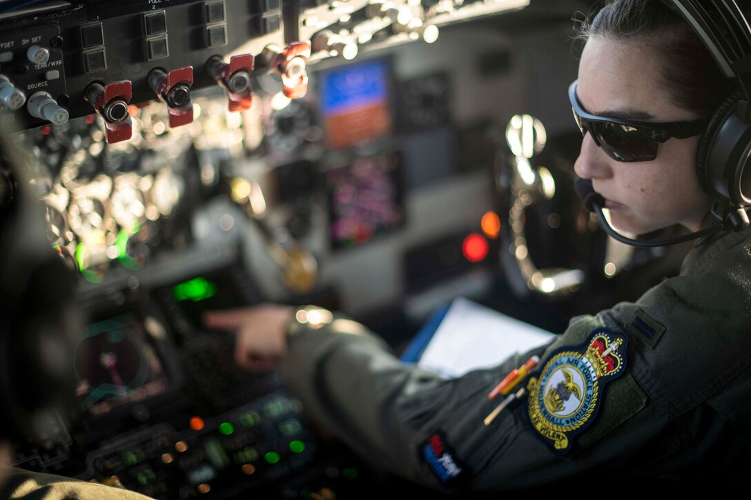 A pilot touches controls in a cockpit.