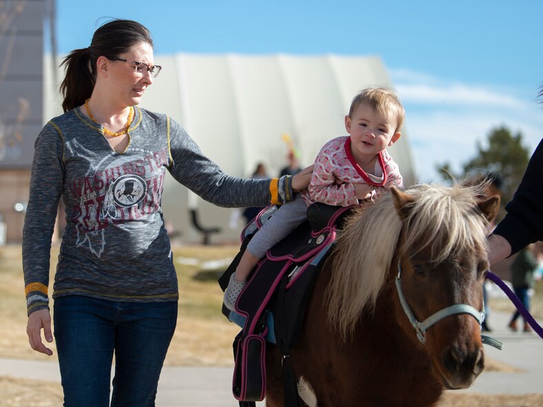 Bethany Lawrence, and her daughter, Ireland, 1, participate in the pony ride event at the annual Children’s Holiday Fest Dec. 7, 2019, at Schriever Air Force Base, Colorado. The free event featured a variety of activities including, pony rides, bouncy houses and face-painting. (U.S. Air Force photo by Airman 1st Class Jonathan Whitely)