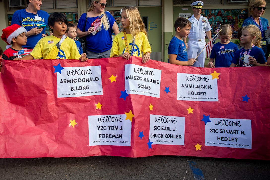 Students with Mokapu Elementary School hold a sign during a U.S. Navy veterans visit to Marine Corps Base Hawaii, Dec. 5, 2019. The Best Defense Foundation returned 6 WWII Pearl Harbor and Naval Air Station Kaneohe Bay survivors to Hawaii for the 78th Commemoration of Pearl Harbor and Naval Air Station Kaneohe Bay which is now MCBH. The heroes returned were Jack Holder US NAVY - Naval Air Station, Kaneohe Bay; Tom Foreman US Navy - USS Cushing; Ira Schab US Navy - USS Dobbin; Stuart Hedley US Navy - USS West Virginia; Donald Long US Navy - Naval Air Station, Kaneohe Bay; and Chuck Kohler US Navy - USS Hornet.