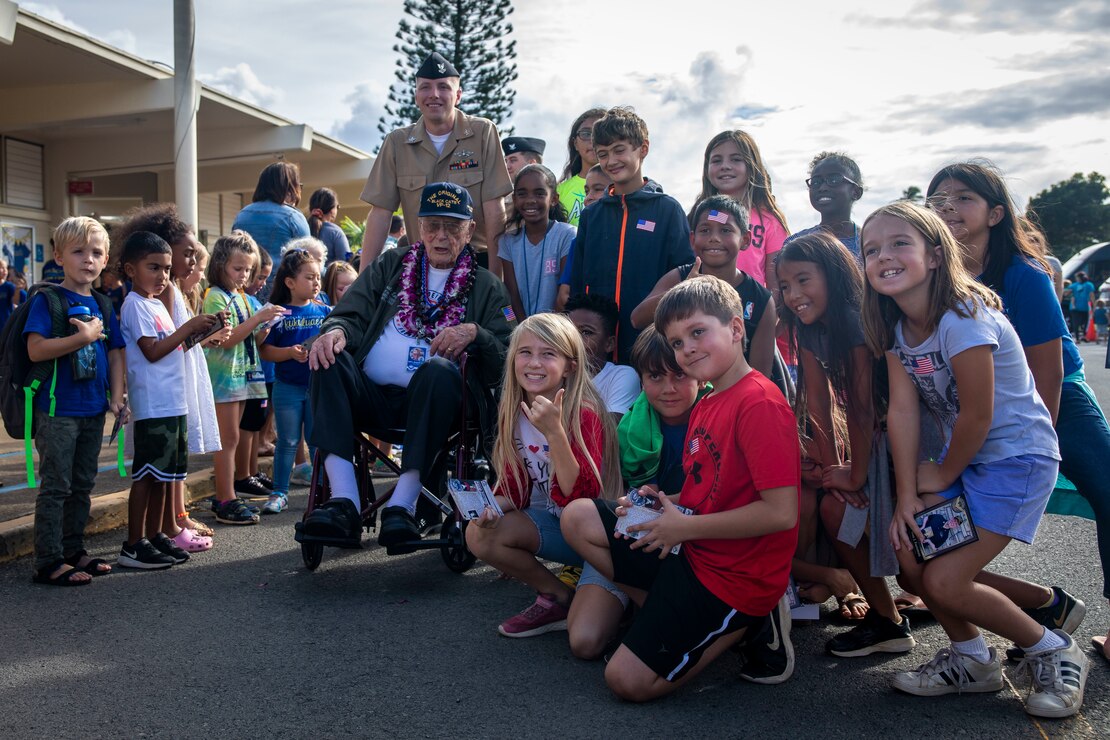 Donald Long, retired U.S. Navy radio operator, and students with Mokapu Elementary School pose for a group photo during Long's visit to Marine Corps Base Hawaii, Dec. 5, 2019. The Best Defense Foundation returned 6 WWII Pearl Harbor and Naval Air Station Kaneohe Bay survivors to Hawaii for the 78th Commemoration of Pearl Harbor and Naval Air Station Kaneohe Bay which is now MCBH. The heroes returned were Jack Holder US NAVY - Naval Air Station, Kaneohe Bay; Tom Foreman US Navy - USS Cushing; Ira Schab US Navy - USS Dobbin; Stuart Hedley US Navy - USS West Virginia; Donald Long US Navy - Naval Air Station, Kaneohe Bay; and Chuck Kohler US Navy - USS Hornet.
