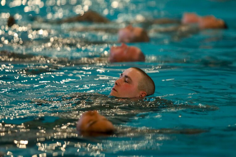 Marine Corps recruits swim in a pool.
