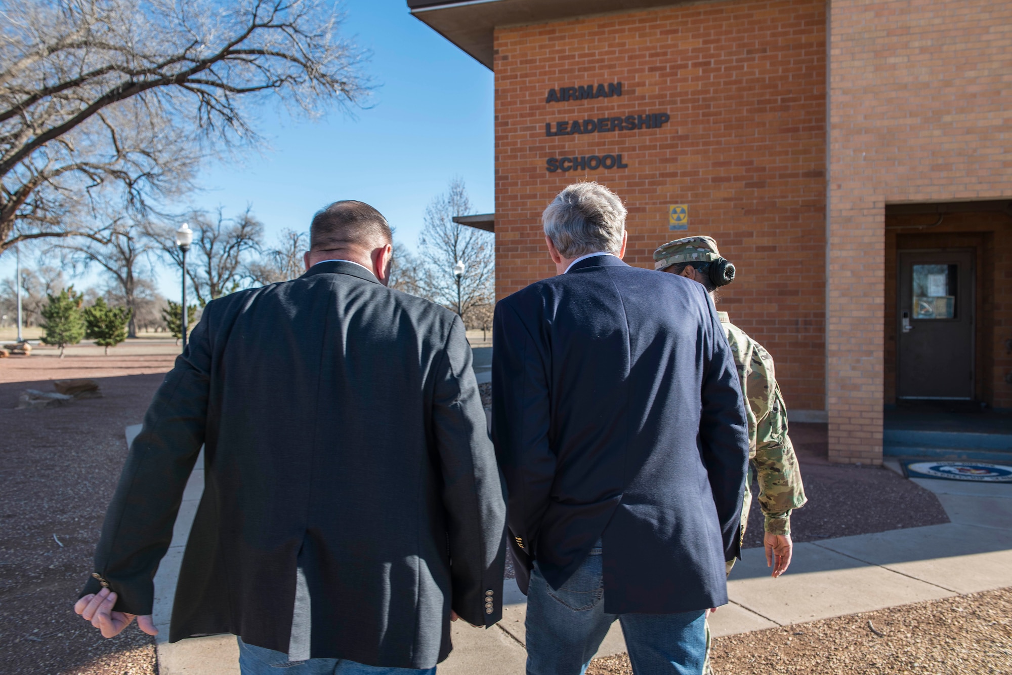 Retired Chief Master Sgts. of the Air Force Eric W. Benken and Jim Finch follow Master Sgt. Dawana Tolbert, 27th Special Operations Force Support Squadron Airman Leadership School commandant, into the Airman Leadership School at Cannon Air Force Base, N.M., Dec. 5, 2019. The 12th and 13th Chief Master Sgts. of the Air Force visited Cannon to share their stories with Air Commandos. (U.S. Air Force photo Senior Airman Vernon R. Walter)