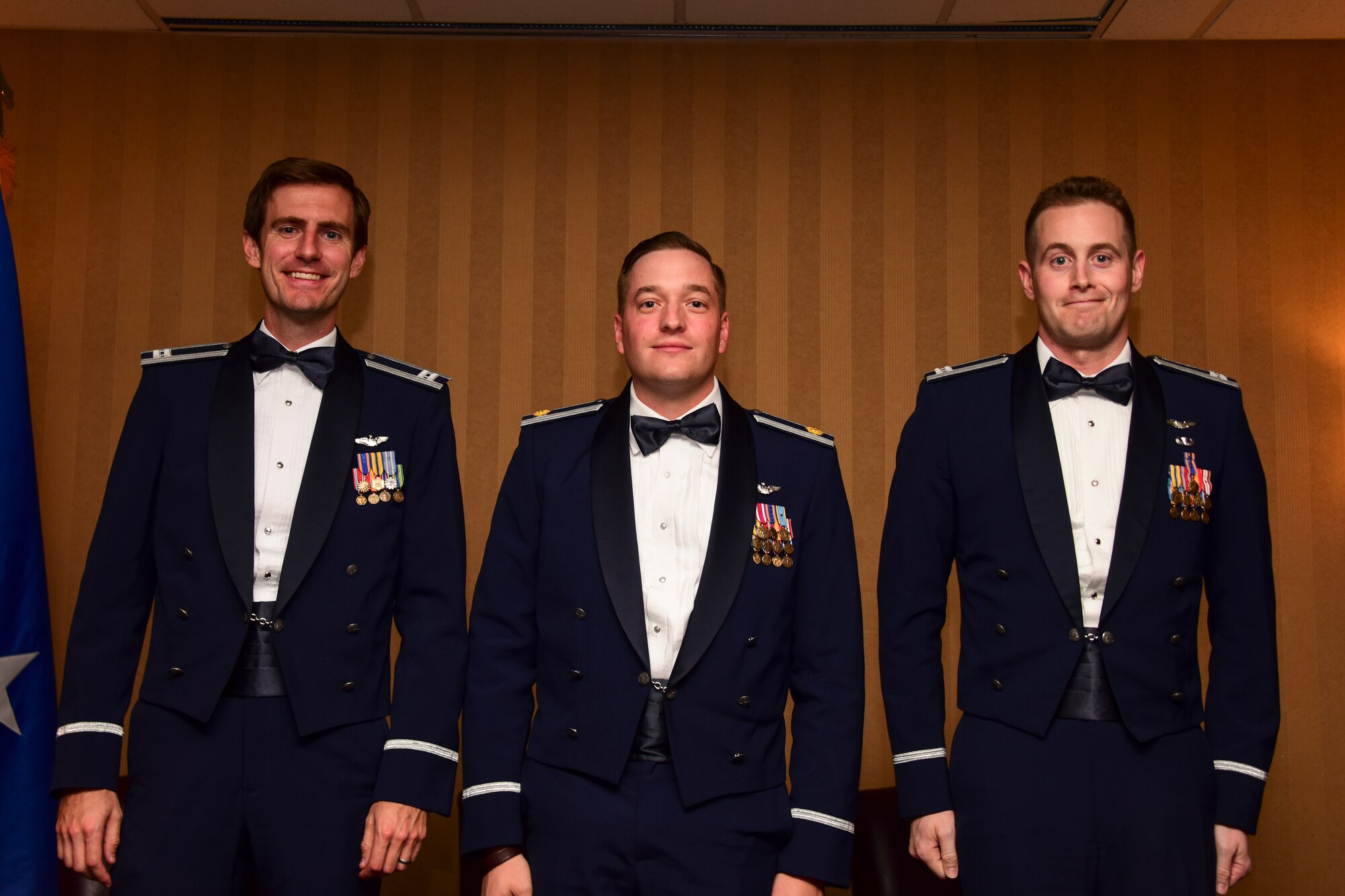 Photo of three Airmen standing on stage