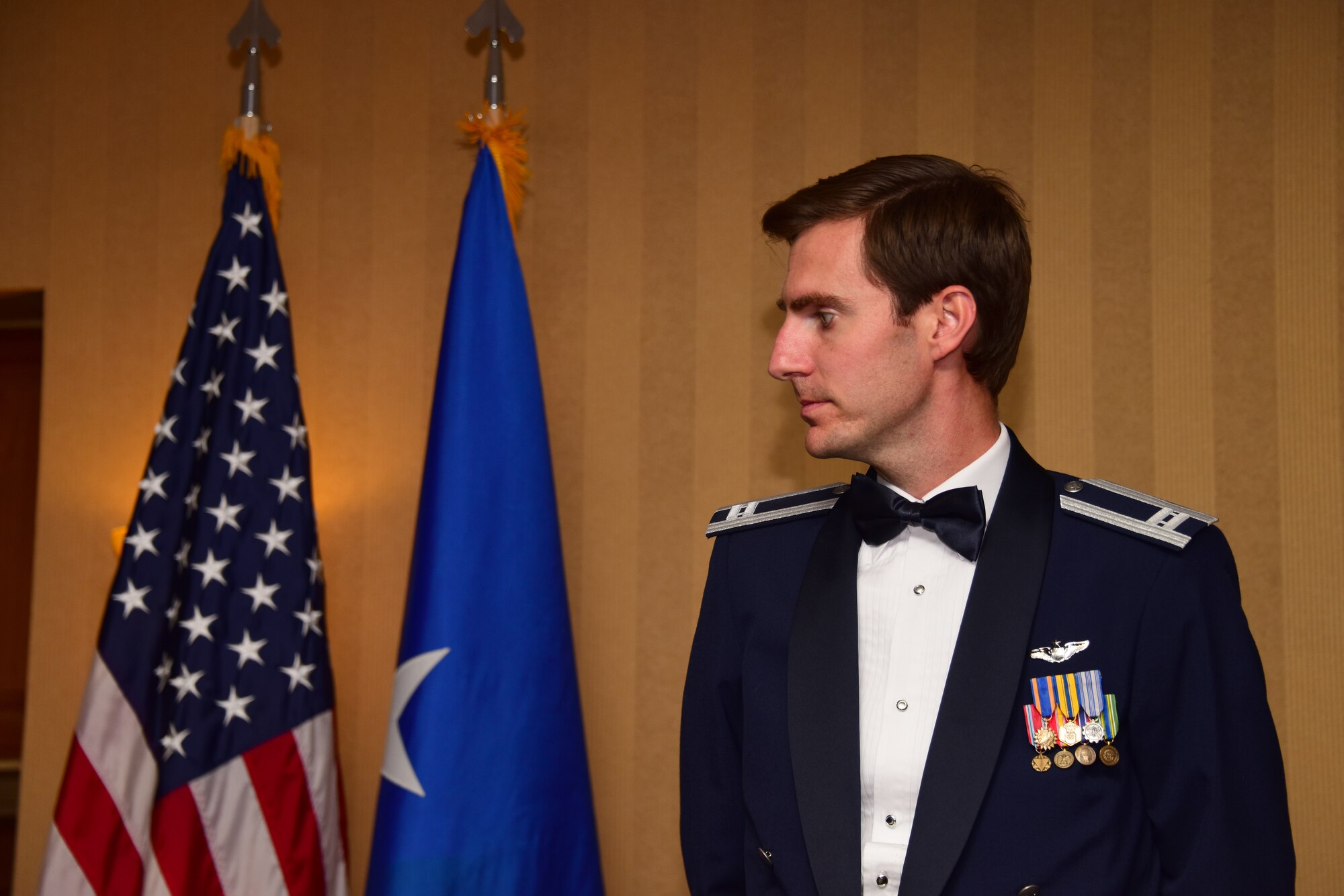 Photo of an Airman next to a U.S. and Air Force flag