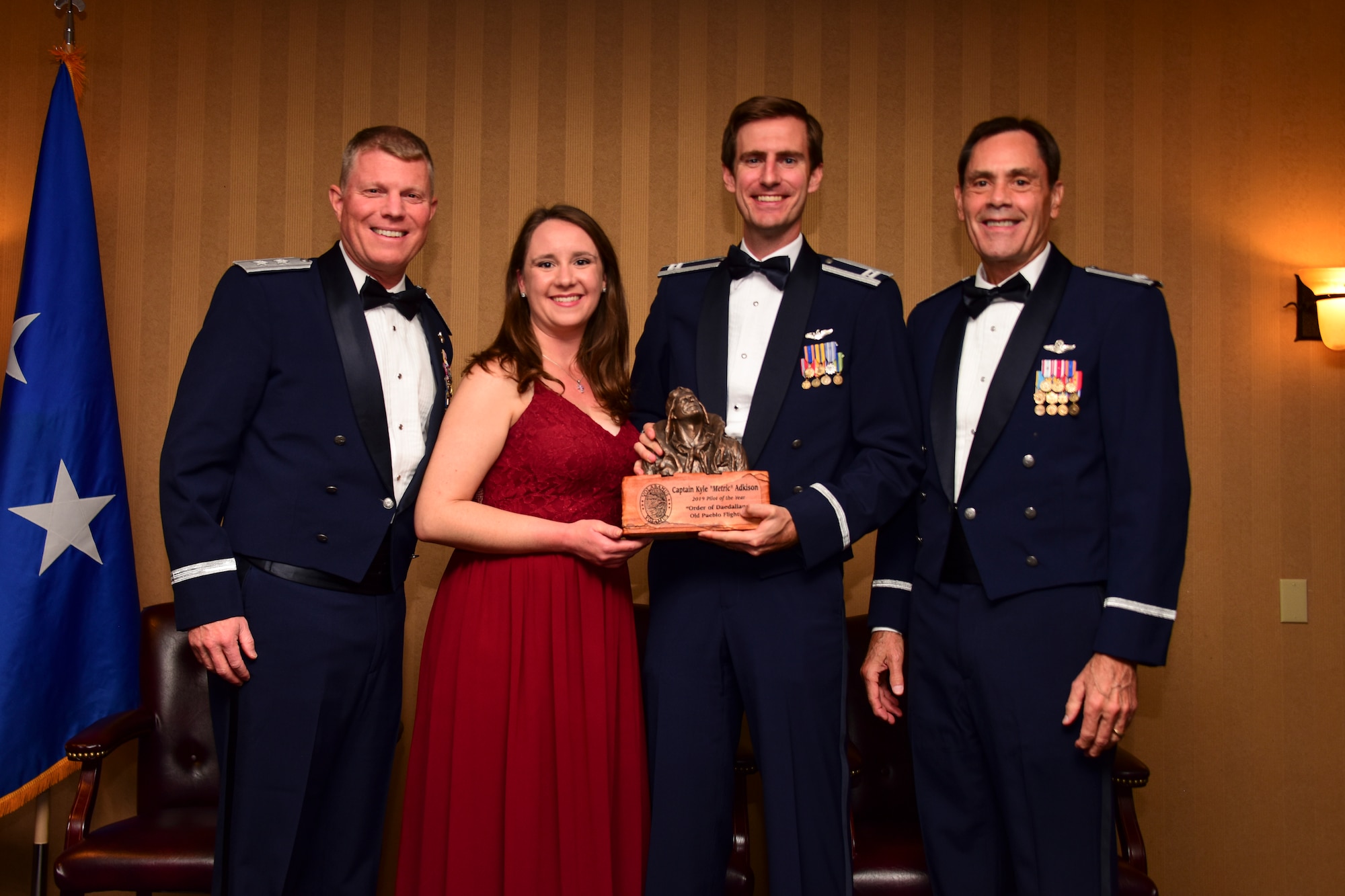 Photo of a U.S. Air Force pilot with his wife, and two other Airmen posing for a group photo with the pilot of the year award
