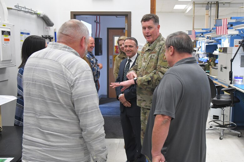 Lt. Gen. Gene Kirkland and Kevin Stamey are talking with several employees in a 524th Electronic Maintenance Squadron  laboratory filled with computer equipment.