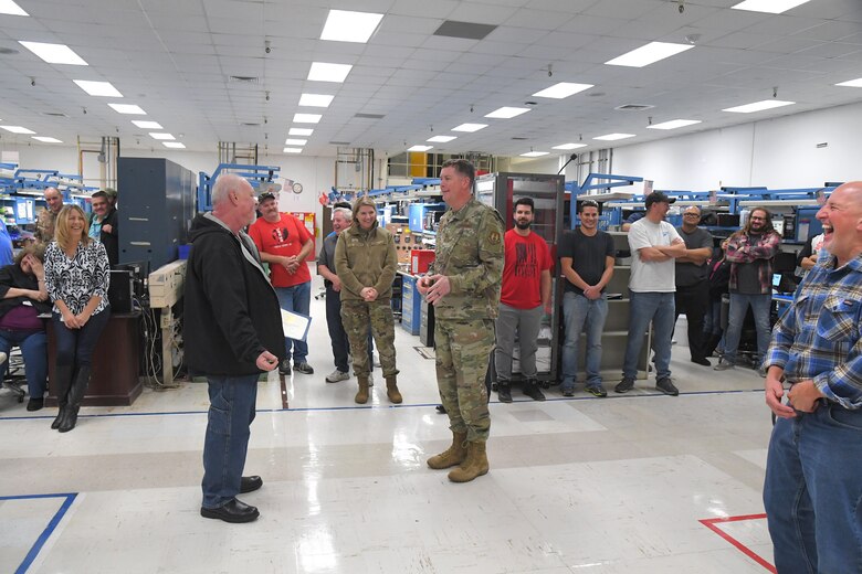 Lt. Gen. Gene Kirkland is recognizing Michael Lind, 524th Electronics Maintenance Squadron, for 40 years of federal service in a 524th EMXS laboratory filled with computer equipment while several other employees and guests watch the presentation.