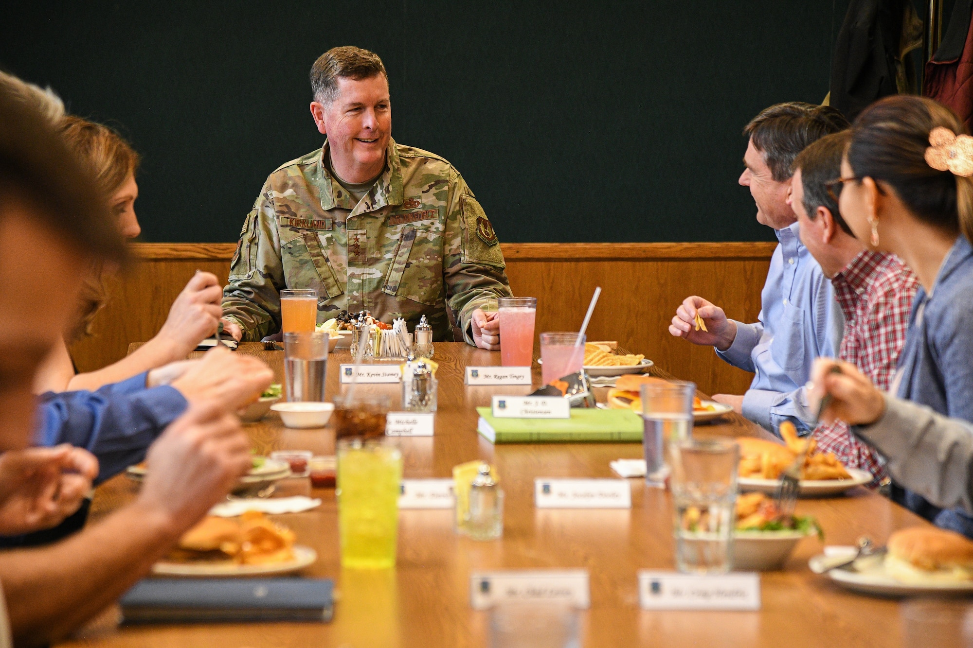 Lt. Gen. Gene Kirkland interacts with several squadron-level leaders gathered at a table eating lunch.