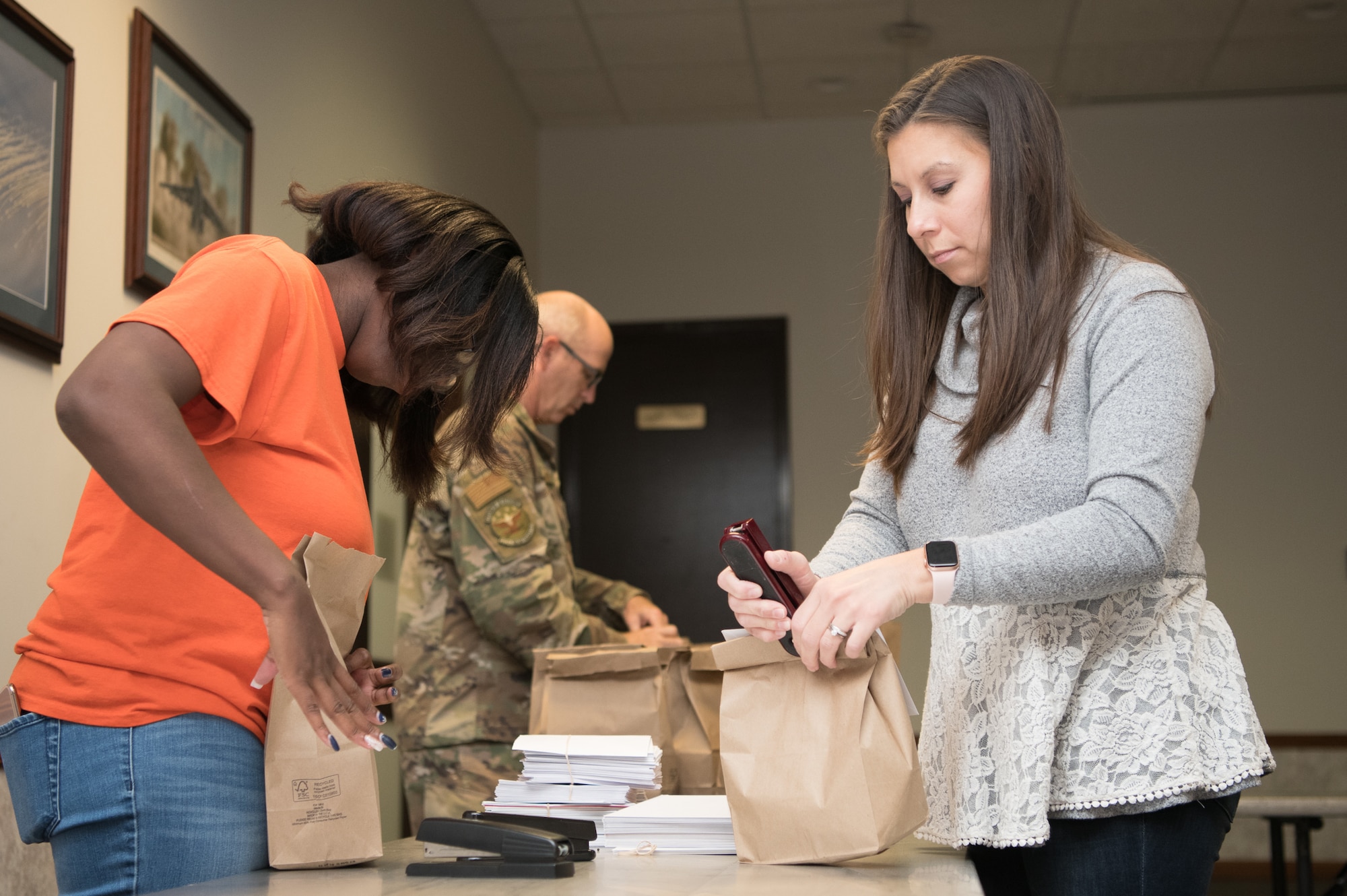 From left to right, Casey Hill and Amanda Habbestad attached greeting cards to bags of cookies during Operation Cookie Drop Dec. 9, 2019, at the 9th Airlift Squadron on Dover Air Force Base, Del. Each bag contains a dozen cookies, along with a greeting card from a member of the local community. (U.S. Air Force photo by Mauricio Campino)