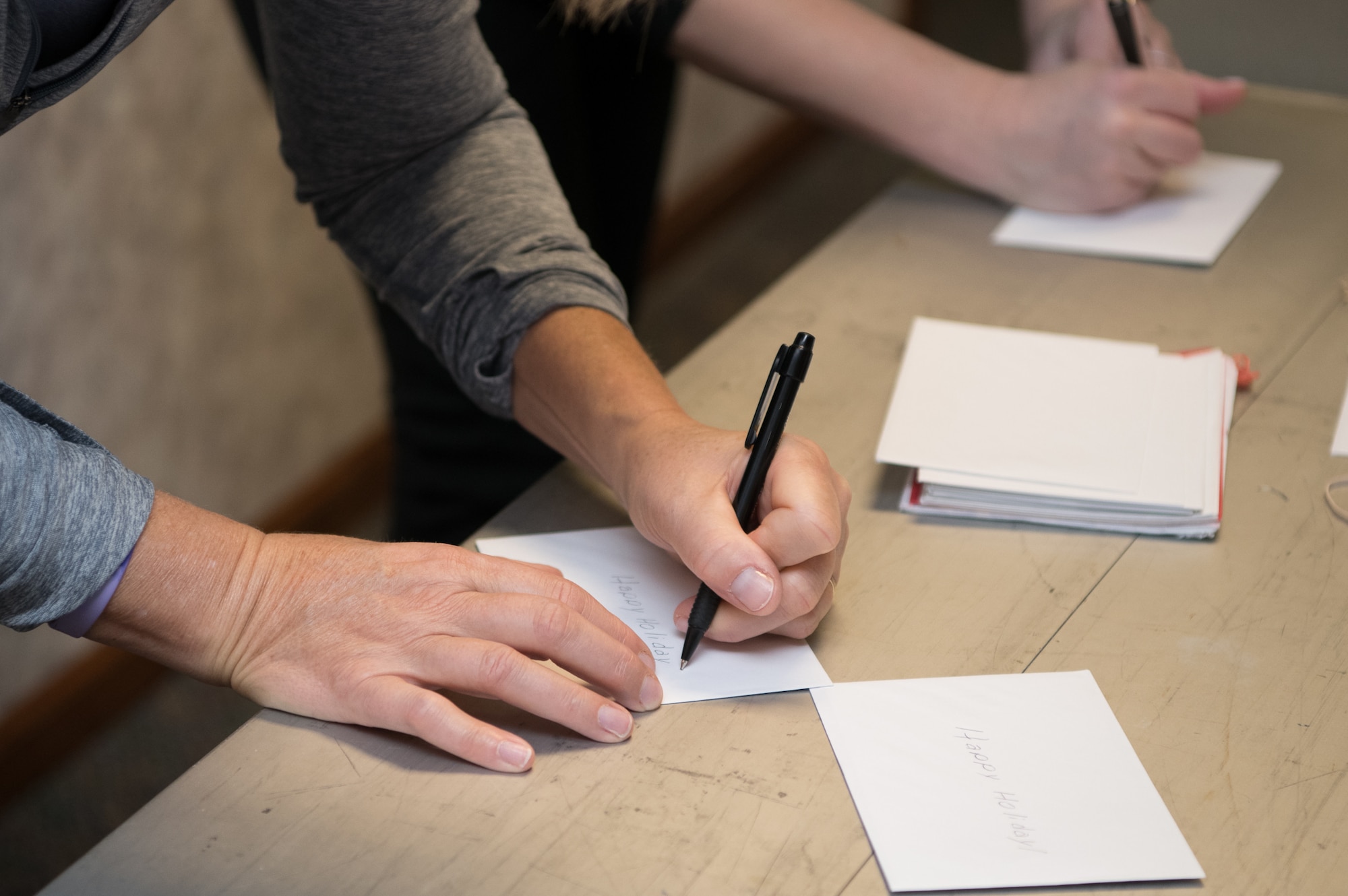 Volunteers add personalized messages to greeting cards that will be attached to bags of cookies and baked goods during Operation Cookie Drop Dec. 9, 2019, at the 9th Airlift Squadron on Dover Air Force Base, Del. Hundreds of greeting cards with personalized messages from members of the local community are received each year. (U.S. Air Force photo by Mauricio Campino)