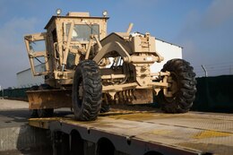 Staff Sgt. Victor Cardona, movement noncommissioned officer, 103rd Expeditionary Command, loads a 120M Motor Grader onto a trailer at the Syrian Logistics Cell operations center, Erbil, Iraq, Dec. 3, 2019. Once the vehicle is loaded, it will be delivered to Syria.