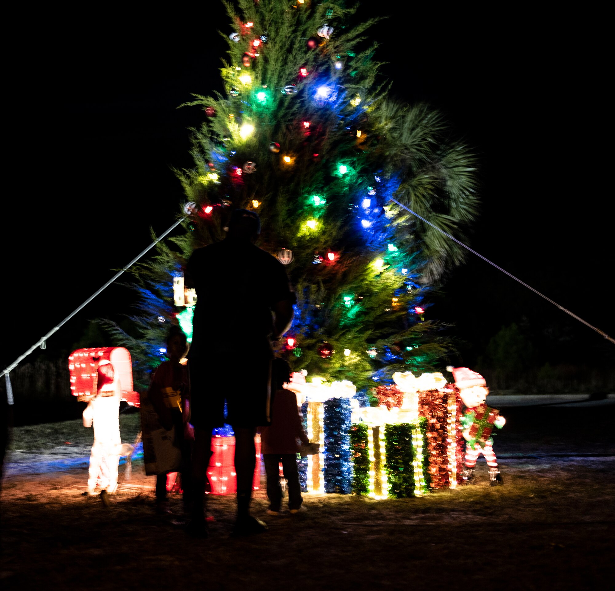 A family poses for personal photos at the 325th Force Support Squadron holiday tree lighting ceremony at Tyndall Air Force Base, Florida, Dec. 6, 2019. The event consisted of the base commander, Col. Brian Laidlaw, lighting the big tree and also included carols sung by the Mosley High School Choir, crafts, and a visit from Santa Claus. (U.S. Air Force photo by Staff Sgt. Magen M. Reeves)