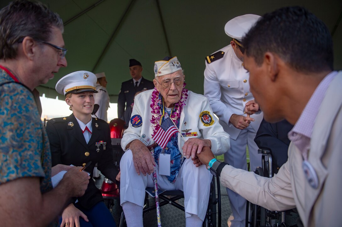 A veteran receives a small American flag as a group of people look on.