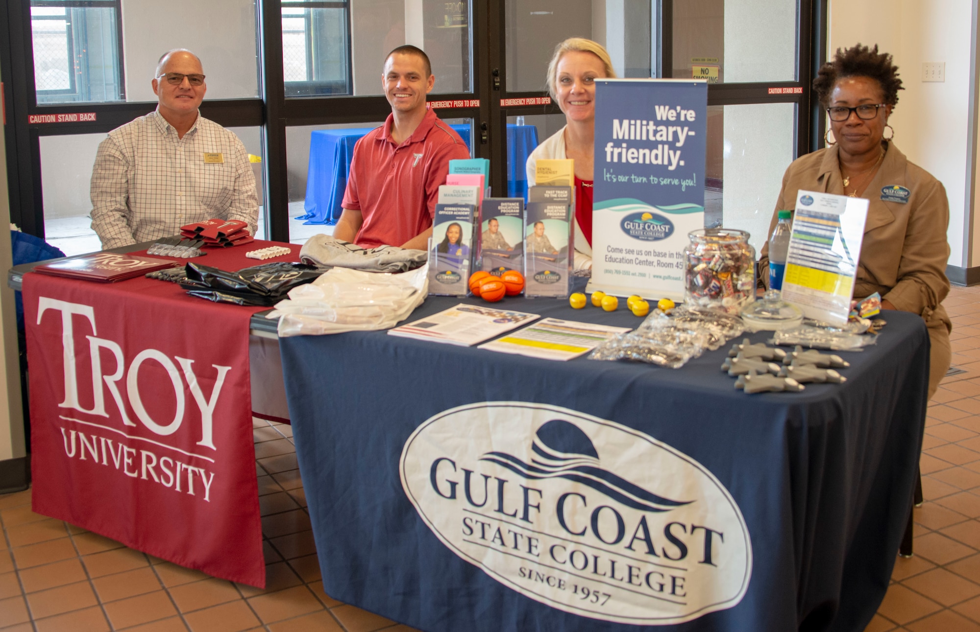 Representatives from the base education office, Troy University, Embry Riddle Aeronautical University, and Gulf Coast State College sit at the Base Exchange food court to answer questions and assist students with enrollment at Tyndall Air Force Base, Florida, Dec. 9, 2019. The 325th Force Support Squadron hosted the education outreach event to help current and prospective students navigate education benefits, on-base schools, and the variety of degree programs offered. (U.S. Air Force photo by 2nd Lt. Kayla Fitzgerald)