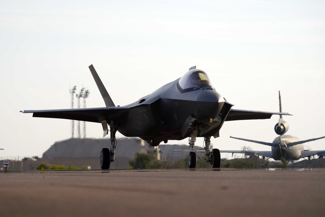 A U.S. military fighter jet sits on a runway near other aircraft.